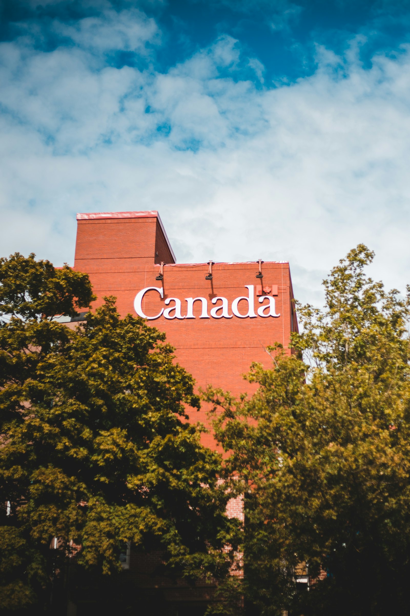 加拿大红砖建筑上的 Canada 字样，夏日绿树环绕