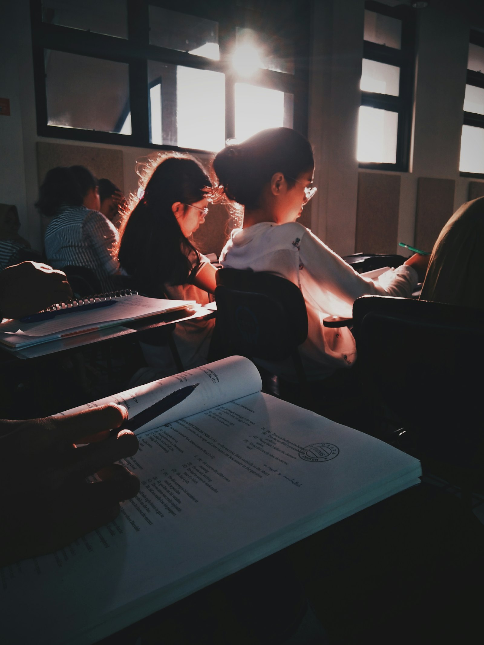 学生在教室里认真看书写字,阳光从窗户射入课室